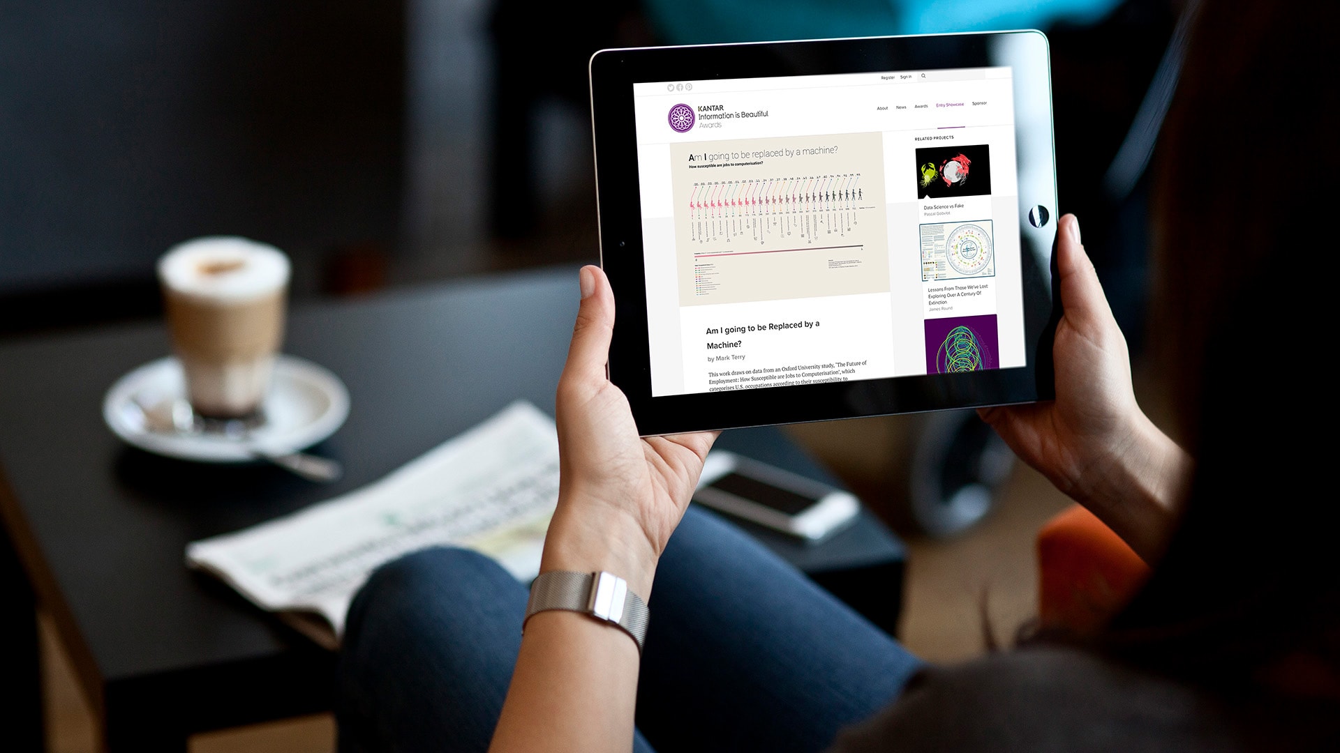 A photograph of a woman holding an electronic tablet displaying the 'Information is Beautiful' Awards Shortlisted Infographic